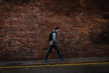 Man walking along the street with brick wall behing them Case Study