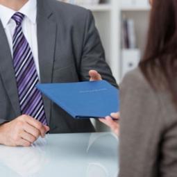 Woman handing folder over to a man News Article